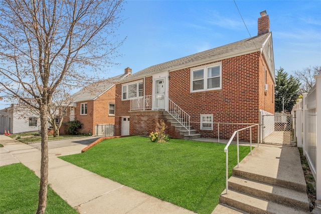 view of front facade featuring a gate, a chimney, fence, a front yard, and brick siding