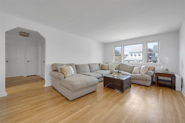 living area with arched walkways and light wood-style floors