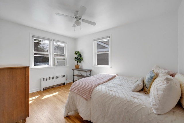 bedroom featuring radiator heating unit, wood finished floors, baseboards, cooling unit, and ceiling fan