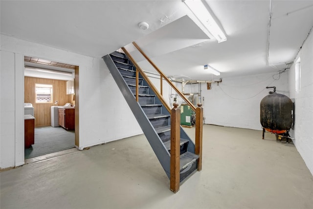 basement featuring washing machine and clothes dryer, stairs, and heating fuel