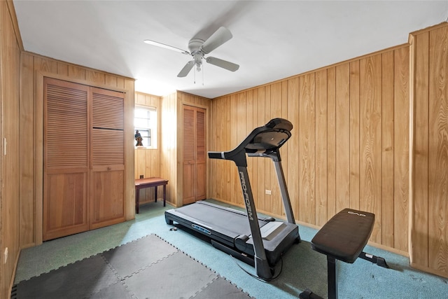 workout area featuring wooden walls, carpet floors, baseboards, and ceiling fan