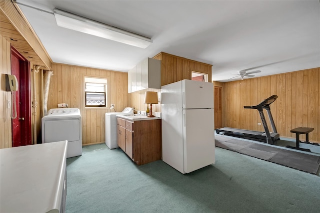 kitchen featuring washer / clothes dryer, wooden walls, and freestanding refrigerator
