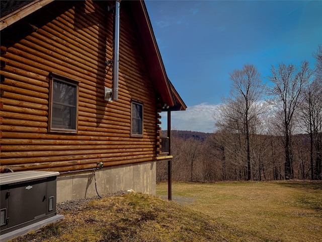 view of side of home featuring a yard, a view of trees, and log siding