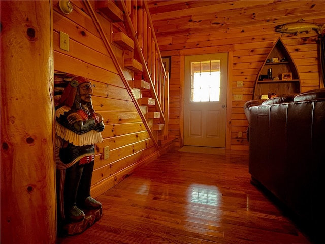 doorway to outside with wood finished floors, wood walls, and stairway