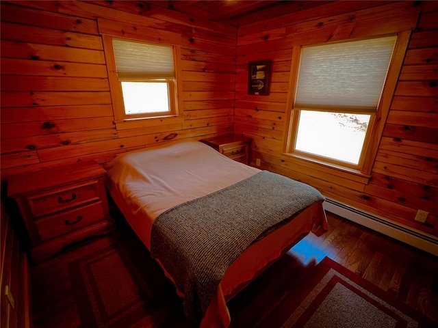bedroom with wood walls, a baseboard radiator, and wood finished floors