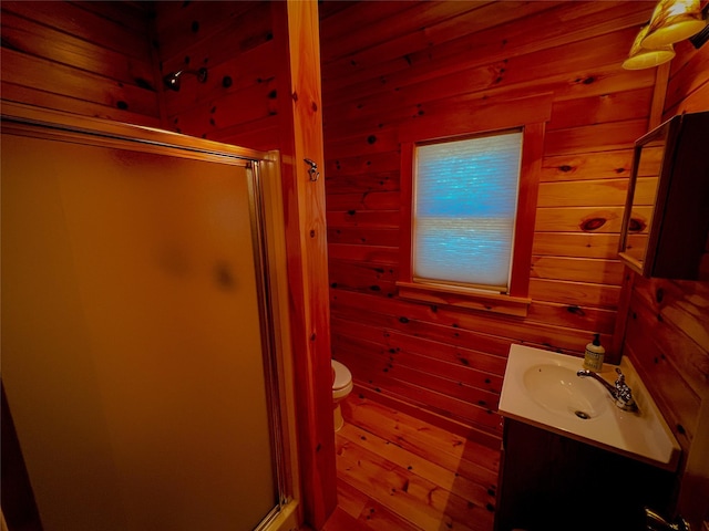 full bath featuring wood walls, vanity, a shower stall, and toilet