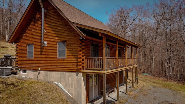 view of home's exterior with central AC, a shingled roof, and log exterior