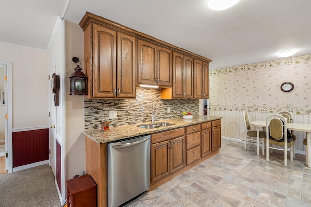 kitchen with stainless steel dishwasher, a sink, light stone counters, and brown cabinetry