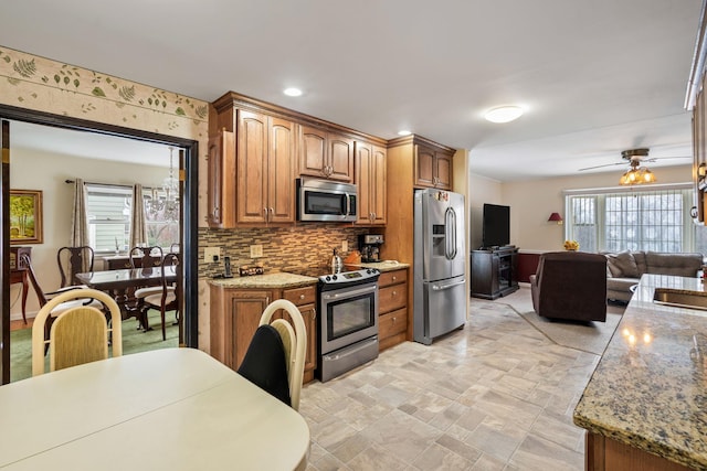 kitchen featuring light stone counters, tasteful backsplash, brown cabinets, and stainless steel appliances