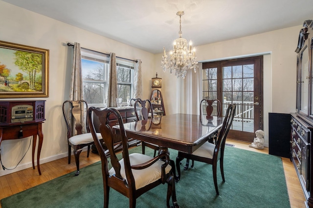 dining space with an inviting chandelier, baseboards, wood finished floors, and a healthy amount of sunlight