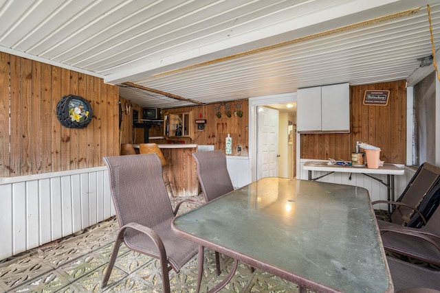 dining space featuring a bar and wood walls