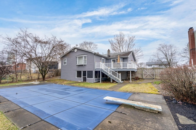 back of house featuring a fenced in pool, a chimney, a deck, stairway, and a fenced backyard