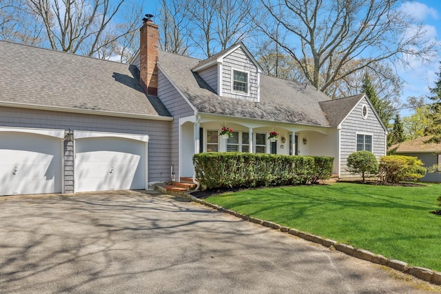 cape cod-style house featuring a porch, aphalt driveway, a chimney, a garage, and a front lawn