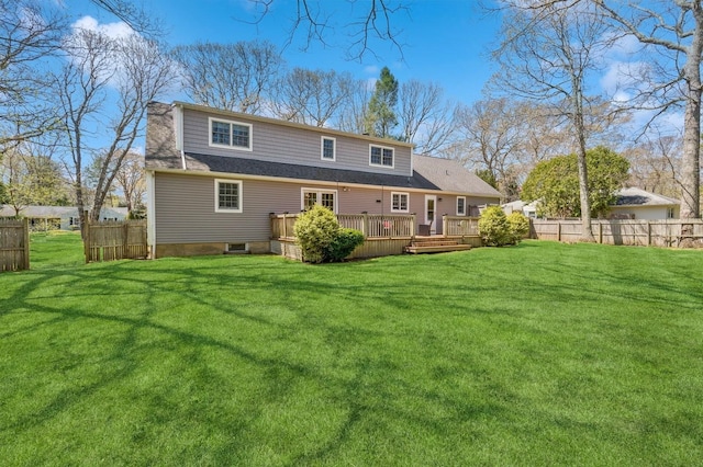 rear view of property with a lawn, fence, and a wooden deck