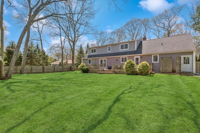 back of property with a yard, a deck, fence, and a chimney