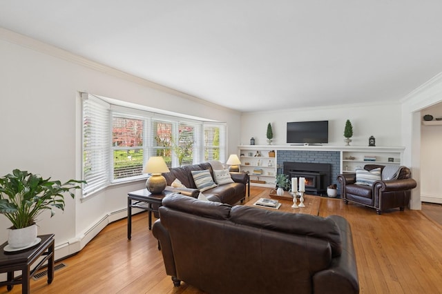 living area featuring crown molding, a fireplace, and light wood-type flooring