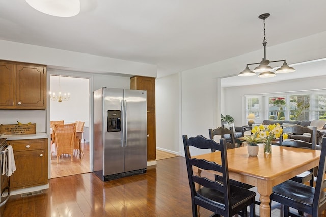 dining room with dark wood-style flooring, an inviting chandelier, and visible vents
