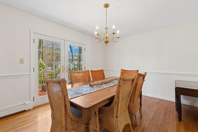 dining area with a notable chandelier, light wood-type flooring, french doors, and a baseboard radiator