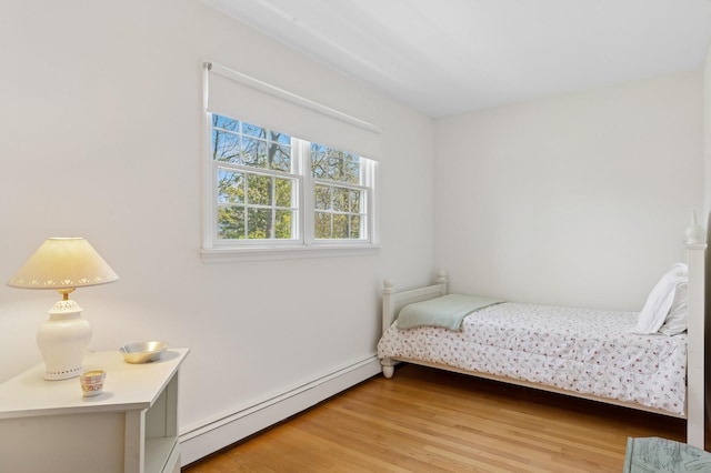 bedroom featuring baseboards, baseboard heating, and light wood-type flooring