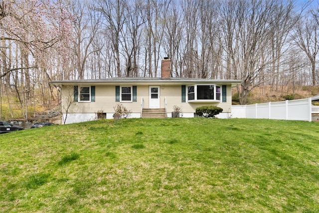 back of property featuring entry steps, a chimney, fence, and a lawn