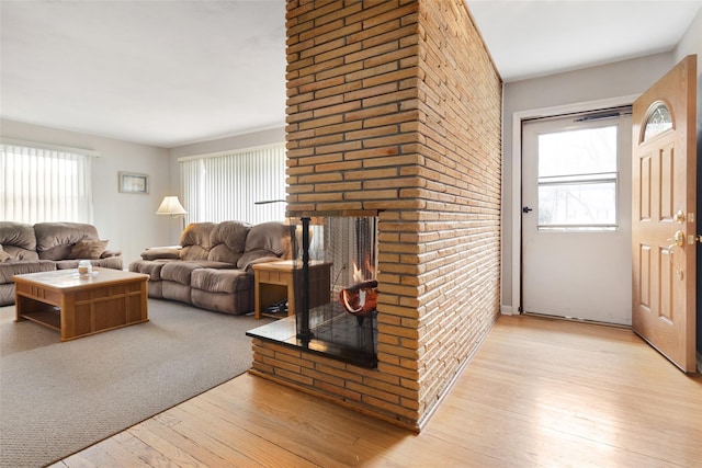 living room featuring light wood-style flooring, a brick fireplace, and plenty of natural light