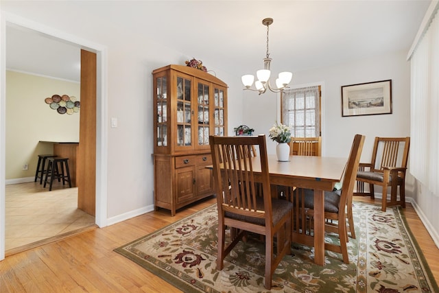 dining room with light wood finished floors, baseboards, and an inviting chandelier