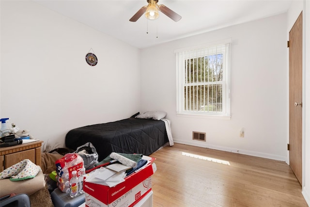 bedroom with baseboards, light wood-style flooring, visible vents, and a ceiling fan