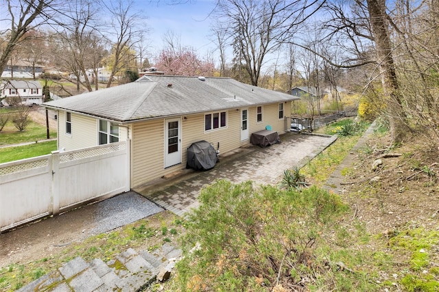 back of house featuring a patio area, fence, and roof with shingles