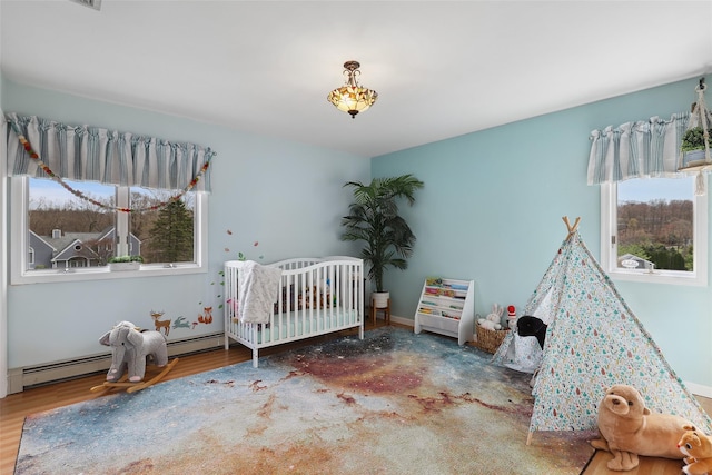 13 Cross Rd, Cortlandt Manor, NY 10567 - bedroom featuring a nursery area, a baseboard heating unit, and wood finished floors