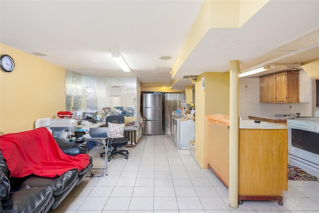 3518 Clarendon Rd, Brooklyn, NY 11203 - kitchen featuring white range with electric cooktop, brown cabinetry, light tile patterned floors, light countertops, and freestanding refrigerator