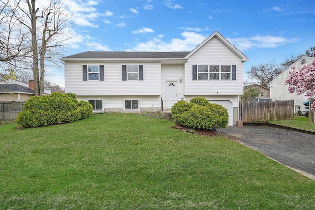 bi-level home with a front yard, driveway, fence, and an attached garage