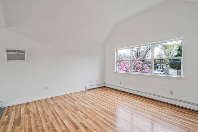 spare room featuring baseboard heating, light wood-type flooring, a wall unit AC, and vaulted ceiling