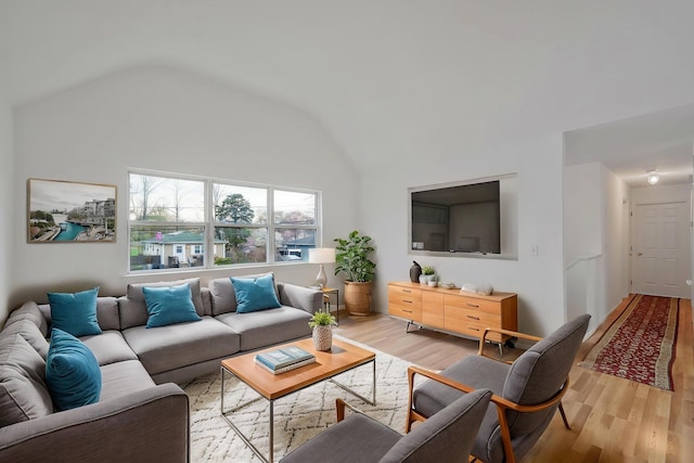 living area with light wood-type flooring and vaulted ceiling