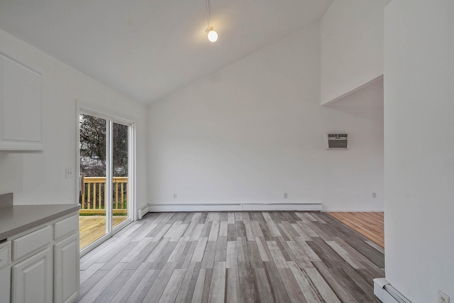 unfurnished dining area featuring an AC wall unit, baseboards, light wood-type flooring, and baseboard heating