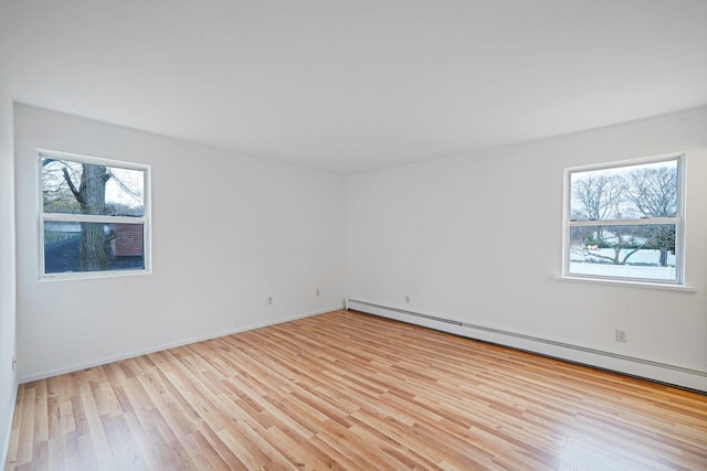 spare room with a baseboard radiator, baseboards, and light wood-style floors