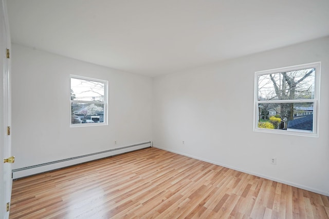 unfurnished room featuring baseboards, a baseboard heating unit, and wood finished floors