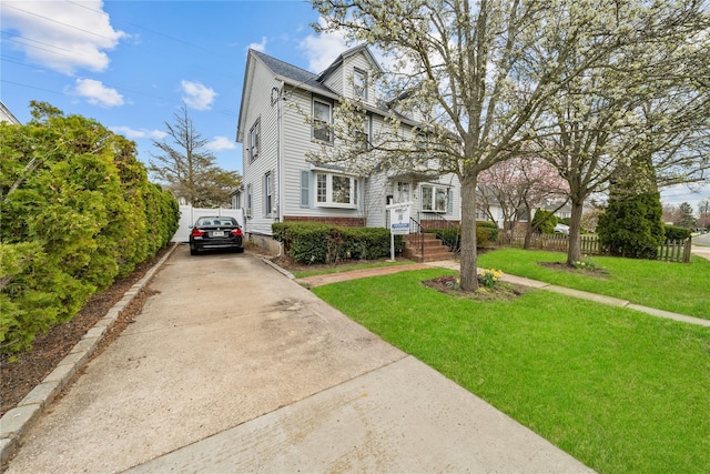 view of front of home with fence, a front yard, and concrete driveway