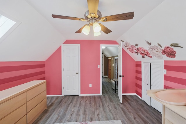 additional living space featuring lofted ceiling, wood finished floors, a ceiling fan, and a sink