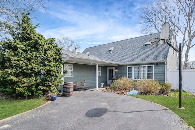 view of front of home with a front yard, fence, a patio area, and roof with shingles