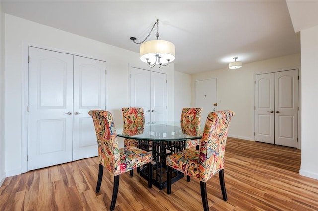 dining space with a chandelier, wood finished floors, and baseboards