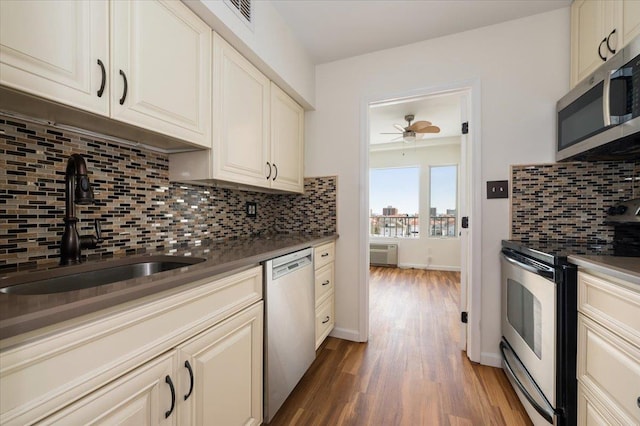 kitchen with ceiling fan, tasteful backsplash, appliances with stainless steel finishes, wood finished floors, and a sink