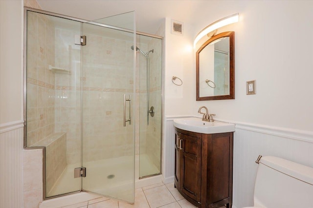 full bath with visible vents, tile patterned floors, toilet, a shower stall, and a wainscoted wall