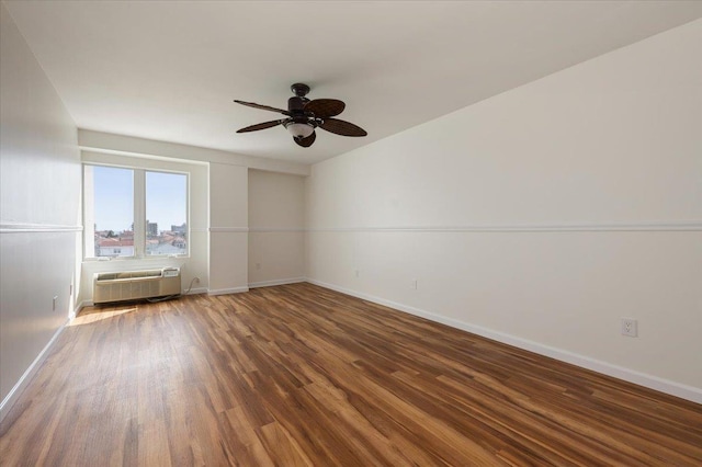 empty room with baseboards, a ceiling fan, wood finished floors, and a wall mounted air conditioner