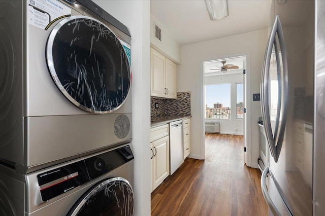 laundry room with laundry area, ceiling fan, dark wood finished floors, visible vents, and stacked washing maching and dryer