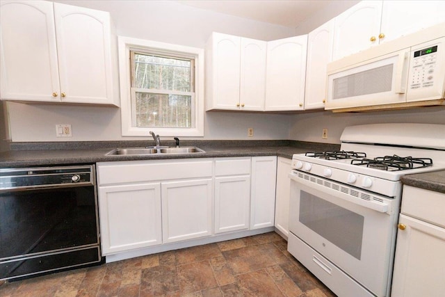 700 Sackett Lake Rd, Monticello, NY 12701 - kitchen featuring white cabinets, a sink, dark countertops, white appliances, and stone finish flooring