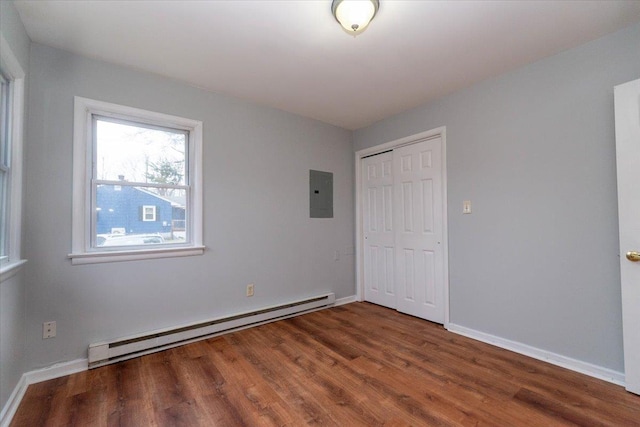700 Sackett Lake Rd, Monticello, NY 12701 - unfurnished bedroom with a closet, electric panel, wood finished floors, a baseboard radiator, and baseboards