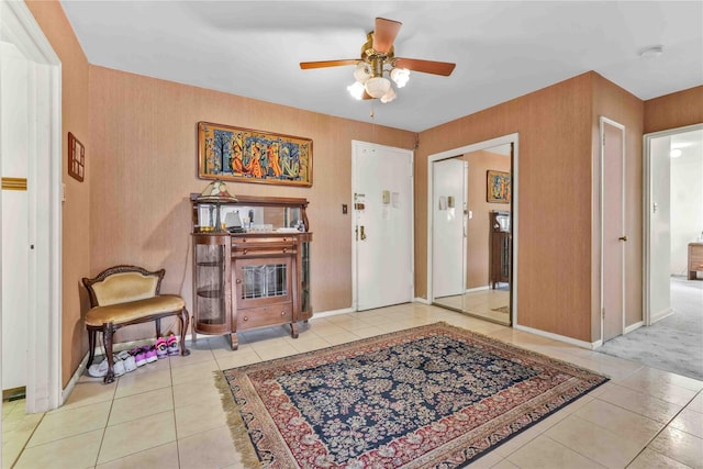 tiled entryway featuring ceiling fan and baseboards