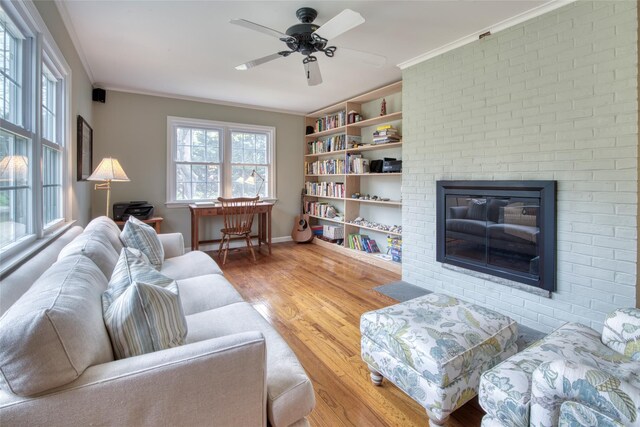 555 Three Waters Ln, Orient, NY 11957 - living area with wood finished floors, a ceiling fan, crown molding, baseboards, and a brick fireplace