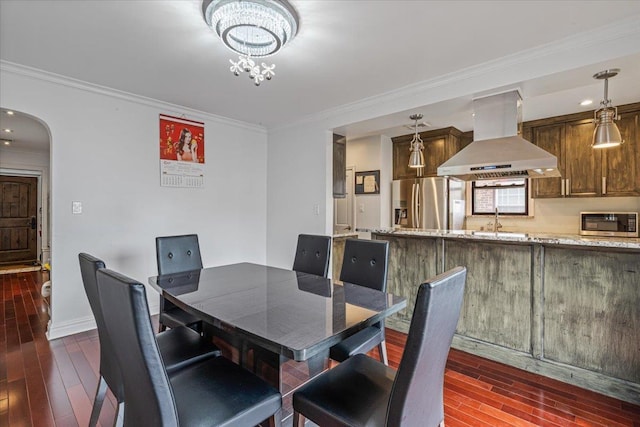 dining area with a chandelier, crown molding, dark wood-style floors, and arched walkways