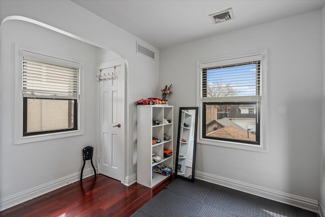 interior space featuring dark wood-style flooring, visible vents, baseboards, and arched walkways